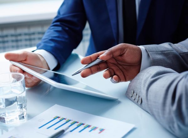 Image of businessmen hands during discussion of data in touchpad at meeting